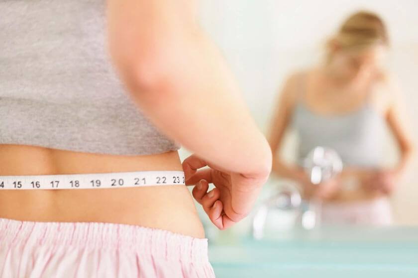Woman measuring her waist.