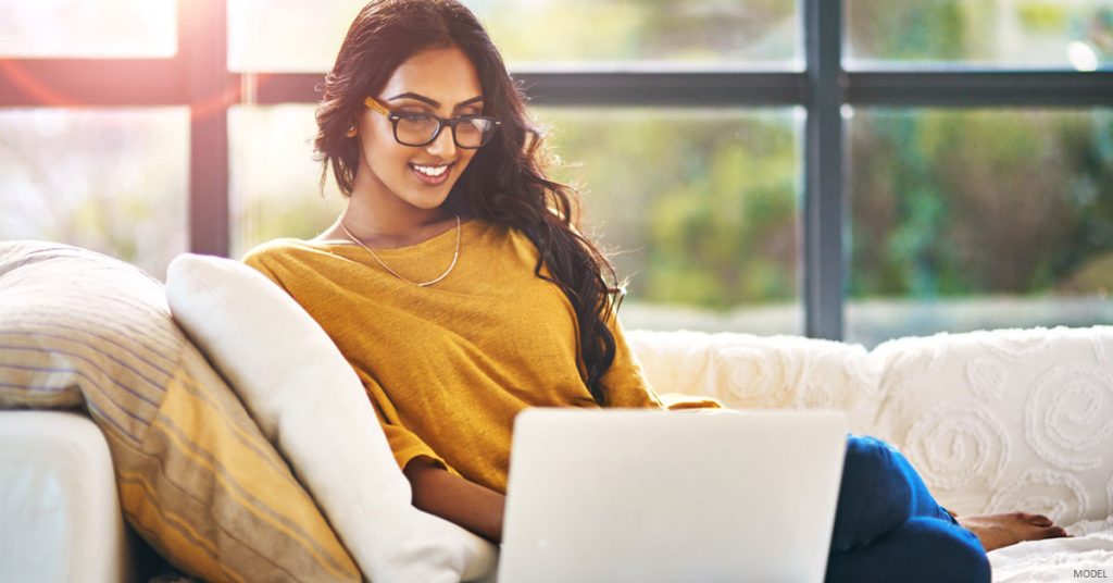 Woman in The Woodlands, TX sitting on couch looking at laptop.