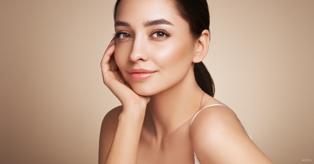 Woman with smooth and wrinkle-free skin resting her chin in her hand (model)