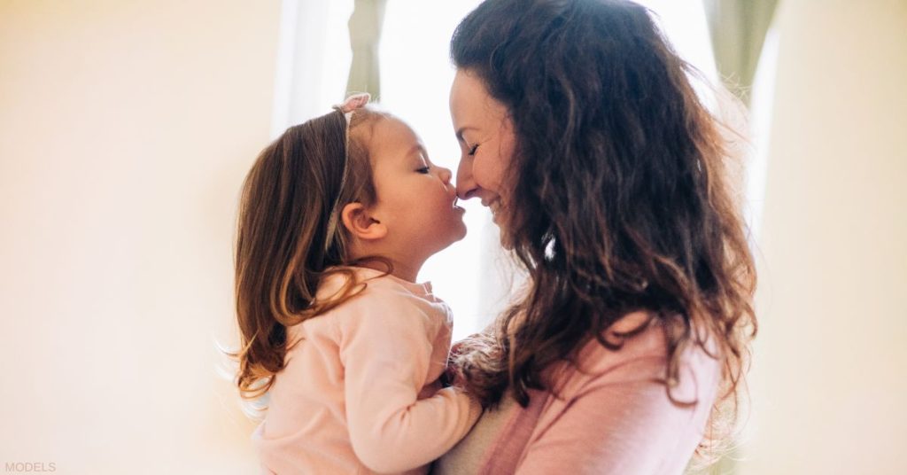 Mother holding her daughter and smiling (model)